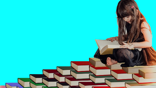Ung jente sitter omgitt av mange bøker i forskjellige farger