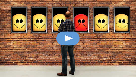 man looking at windows with smiley faces and one non-smiley face