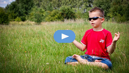 ung pojke som bär solglasögon som mediterar i ett öppet fält