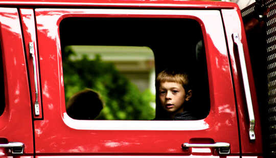 Лицо ребенка в расширенном окне кабины красного грузовика