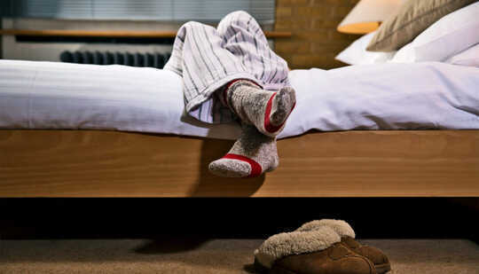 Ноги человека свешиваются за край кровати