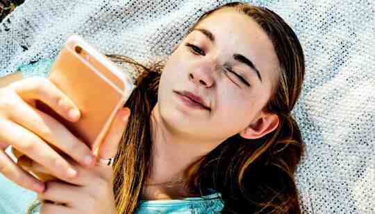 Seorang remaja membaca teleponnya dengan ekspresi bingung di wajahnya