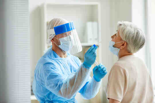 卫生保健工作者对患者进行 COVID 拭子测试。