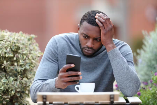 mukhang stress na stress ang isang lalaki habang nakatingin sa phone niya