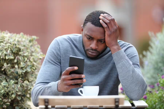 un homme apparemment très stressé en regardant son téléphone