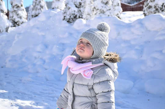 young girl in winter looking up at the sky