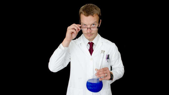 médecin tenant un bécher de liquide bleu