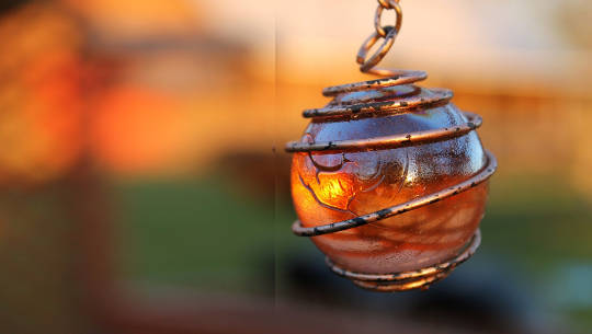 uma esfera brilhante em um pingente com um envoltório de fio de cobre