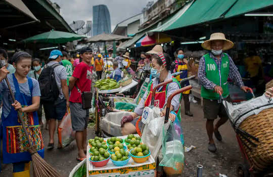 Myyjät myyvät vihanneksia märillä markkinoilla Bangkokissa, Thaimaassa.