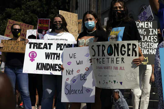 מפגינים מחזיקים שלטים במהלך צעדת נשים בתאריך 17 באוקטובר 2020 בלוס אנג'לס. אלפי נשים התכנסו בערים בארה"ב כדי להתנגד לנשיא דונלד טראמפ ולעמיתיו המועמדים הרפובליקנים בבחירות ב -3 בנובמבר.