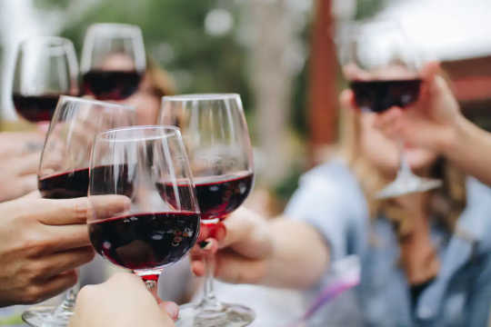 Människor klirrar glas rött vin.