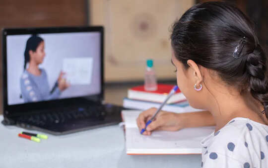 在家学习与在她前面的计算机和显示某事的老师的女孩。