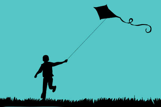 silhouet van een jongen die een vlieger vliegt