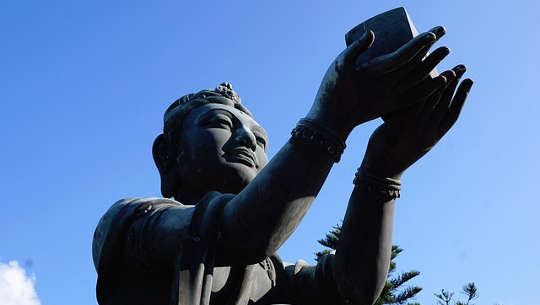 buddha statue holding up a gift to the heavens