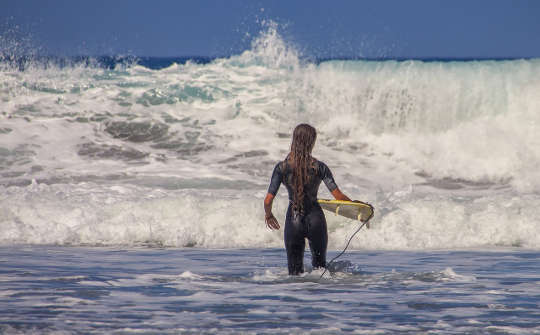 surfista con una pequeña tabla de surf frente a enormes olas