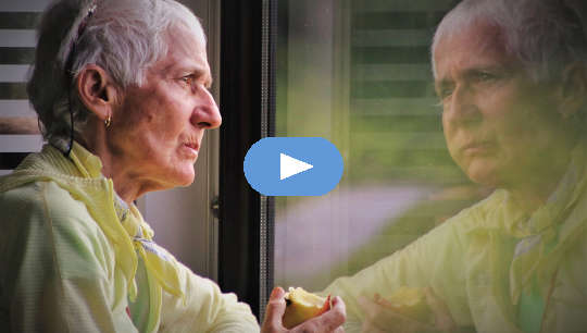 ältere Person, die einen Apfel isst und ihr Spiegelbild in einem Fenster betrachtet