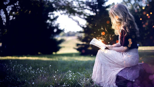 nainen istuu ulkona lukemassa kirjaa