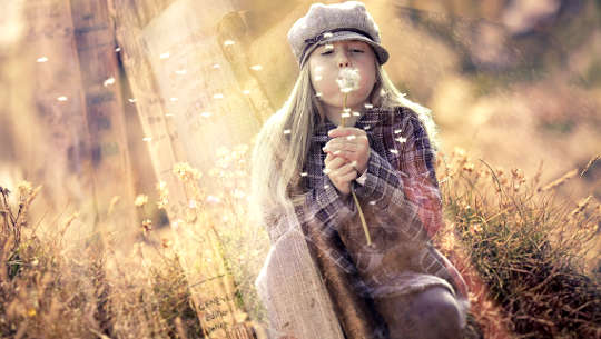 cô gái trẻ thổi trên một bông hoa dành dành làm rơi vãi hạt