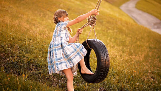 小女孩爬上轮胎秋千