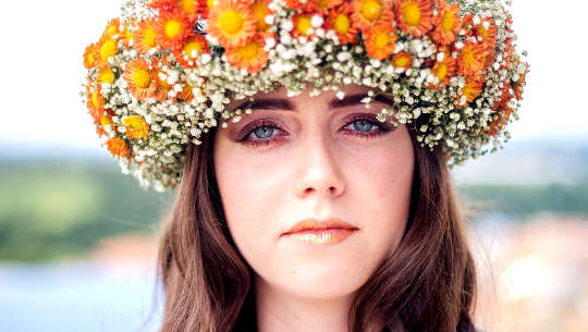 woman wearing a crown of flowers staring with an unwavering gaze