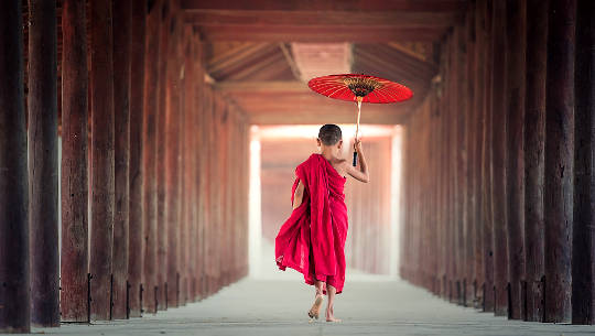 joven monje budista sosteniendo un paraguas