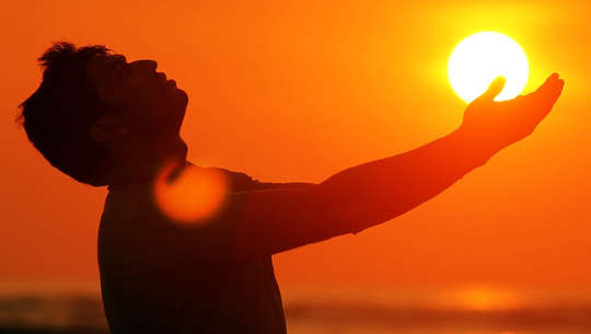 lelaki di luar dengan tangan dihulurkan ke matahari