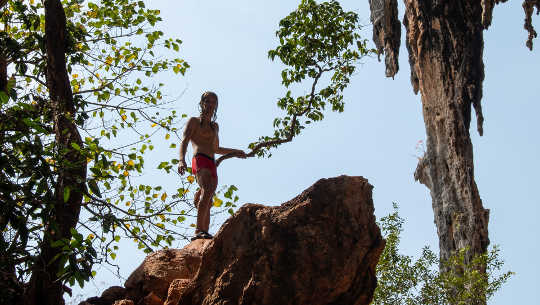 молодий хлопчик піднімається на вершину скелі
