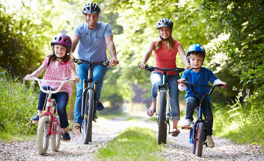 férfi, nő és két kisgyermek biciklizik