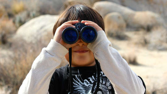 joven mirando a través de binoculares
