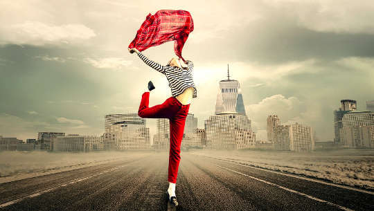 người phụ nữ nhảy múa ở giữa đường cao tốc vắng vẻ với nền đường chân trời của thành phố