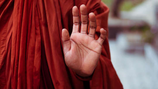 Monk holding up a hand in a mudra gesture