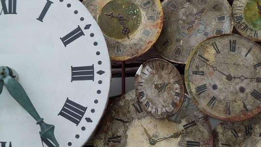novo relógio em primeiro plano com vários relógios antigos em segundo plano