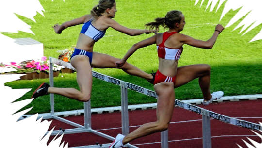 two women track runners jumping a hurdle
