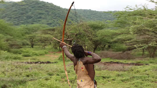 Arqueiro Hadzabe lançando uma flecha de seu arco