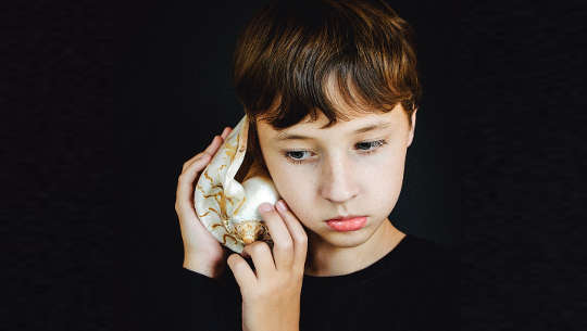fiatal lány egy kagylót tart a füléhez