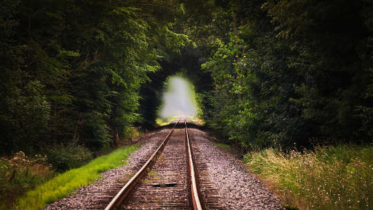 järnvägsspår som leder in till en ljus tunnel