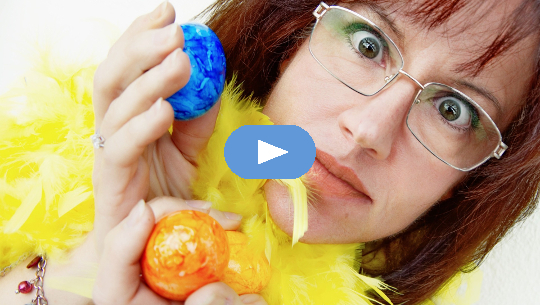 imagen de una mujer sosteniendo dos huevos de colores, con una mirada de sorpresa en su rostro