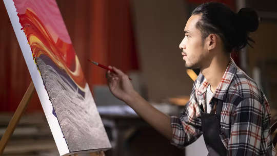한 남자가 스튜디오에서 캔버스에 그림을 그립니다.