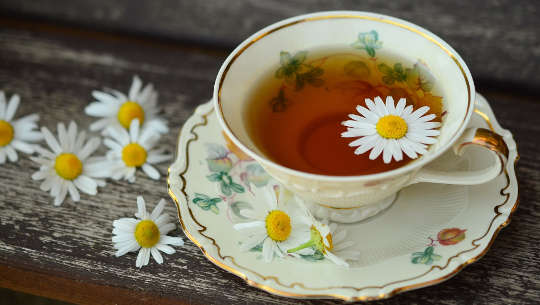 una taza de té con una flor flotando encima en una delicada taza de porcelana