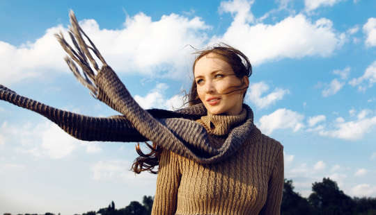 女孩站在外面，圍巾在風中飄揚