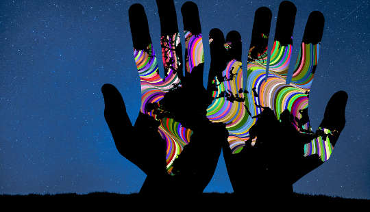 여러 가지 빛깔의 파도에 세계 지도가 찍힌 열린 손