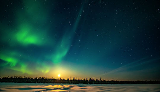 aurora boreal bailando sobre la salida de la luna