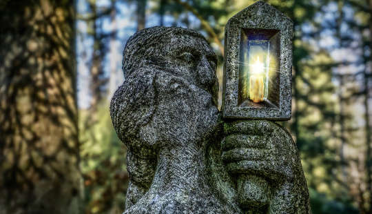 escultura em pedra de um homem e uma mulher segurando uma lanterna