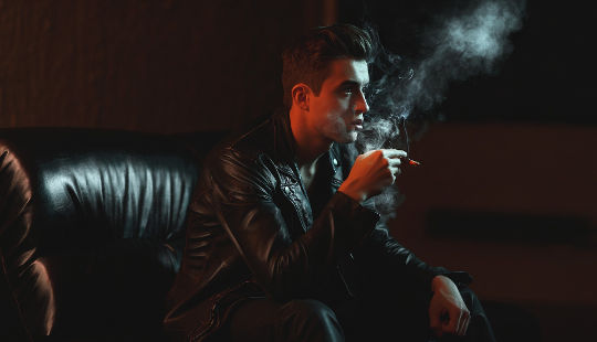 어두운 설정 흡연에 앉아 젊은 남자