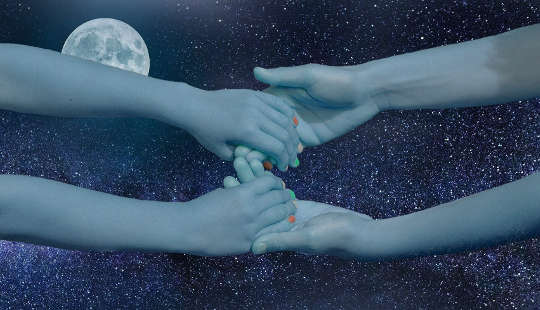 duas mãos de pessoas alcançando e se juntando através do céu e uma lua cheia