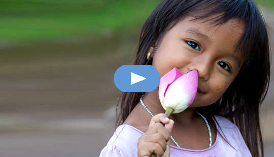 smilende ung jente som holder en uåpnet lotusblomst