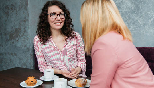 duas mulheres conversando sobre café e muffins