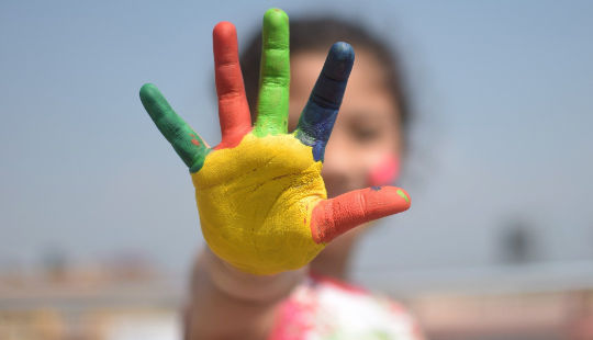 gadis kecil dengan jari-jarinya semua dalam warna yang dilukis dengan tangan yang berbeda