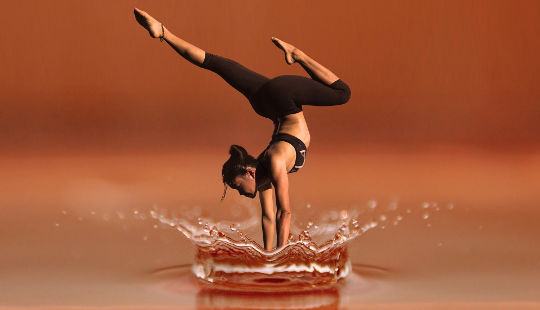 uma mulher em uma pose de ioga de parada de mão na água