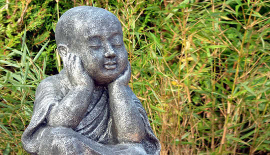 eine Statue eines sitzenden Buddhas in einem Grasfeld